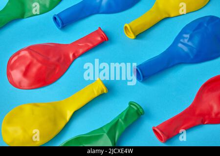 Les ballons multicolores non gonflés sont rouge, jaune, bleu et vert en diagonale sur un fond bleu Banque D'Images