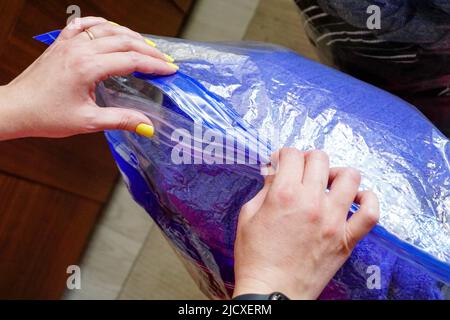 Femme fermant le sac sous vide pour les vêtements avec sa main vue rapprochée Banque D'Images