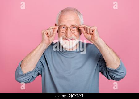 Photo de l'homme de cheveux gris aîné mains lunettes porter une chemise bleue isolée sur fond rose Banque D'Images