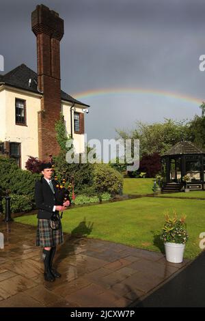 WESTERN House, Ayr, Ayrshire, Écosse, Royaume-Uni. Alistair Brown joue à l'extérieur de la Western House sous la pluie. La Western House est gérée par l'hippodrome d'Ayr et est un lieu primé. La pipette joue dans la pluie avec un arc-en-ciel en arrière-plan Banque D'Images