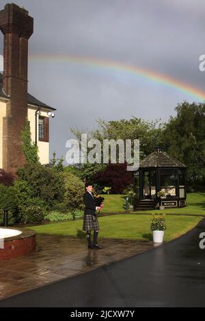 WESTERN House, Ayr, Ayrshire, Écosse, Royaume-Uni. Alistair Brown joue à l'extérieur de la Western House sous la pluie. La Western House est gérée par l'hippodrome d'Ayr et est un lieu primé. La pipette joue dans la pluie avec un arc-en-ciel en arrière-plan Banque D'Images