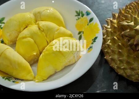Durian frais en emballage sur un plat blanc avec pelage durian sur fond noir de bannière. Roi durien des fruits. Fruits tropicaux. TopView de durien mûr Banque D'Images