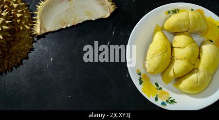 Durian frais en emballage sur un plat blanc avec pelage durian sur fond noir de bannière. Roi durien des fruits. Fruits tropicaux. TopView de durien mûr Banque D'Images