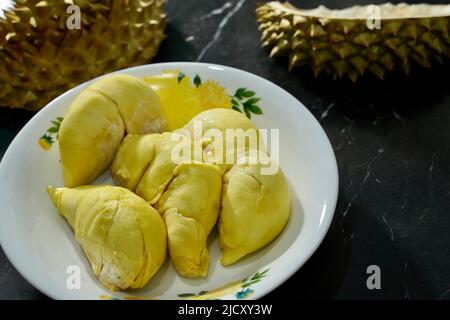 Durian frais en emballage sur un plat blanc avec pelage durian sur fond noir de bannière. Roi durien des fruits. Fruits tropicaux. TopView de durien mûr Banque D'Images