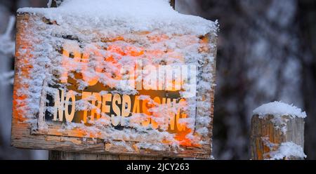 Aucun panneau d'intrusion n'est affiché sur un poteau de clôture en bois en hiver avec un avertissement d'avertissement de neige orange Banque D'Images