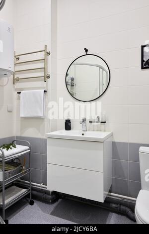 Un miroir rond est suspendu dans la salle de bains au-dessus du lavabo Banque D'Images