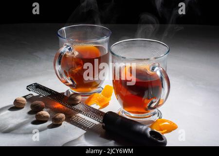 Deux tasses de thé chaud avec peels orange, muscade et râpe sur marbre avec fond sombre. Banque D'Images