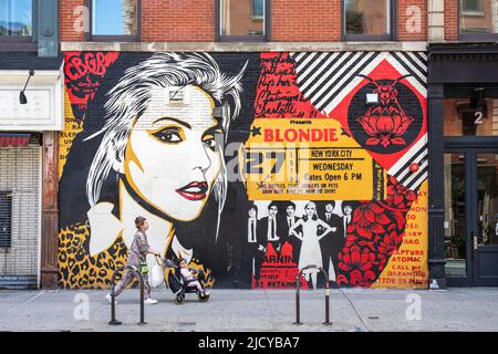 Femme avec un enfant dans une poussette passant la fresque de Blondie par Shepard Fairey dans Bleecker Street, Lower East Side de Manhattan à New York City, Etats-Unis Banque D'Images