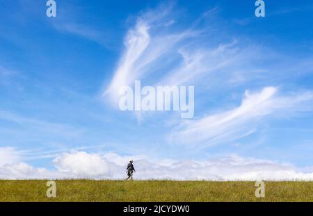 Un homme marche sur la digue à Husum. Être à l'extérieur et être en mouvement est un avantage particulier dans des moments comme celui-ci. Banque D'Images