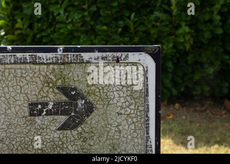 le bord d'angle d'un panneau directionnel est fissuré et ancien avec du flèche pointant vers la droite Banque D'Images