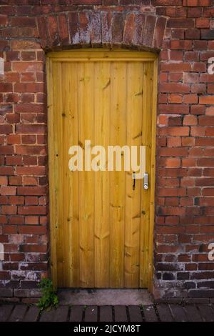 nouvelle porte en bois clair dans un vieux mur avec poignée et porte-clés de sécurité Banque D'Images