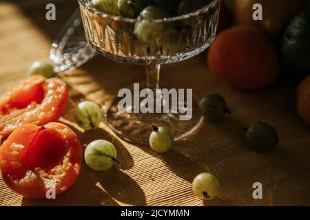 baies et fruits frais sur la table dans une assiette: groseilles à maquereau, raisins de corinthe, citron, lime, orange, abricots. Un mélange de baies locales de saison et de fruits li Banque D'Images