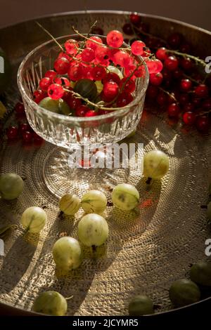 baies et fruits frais sur la table dans une assiette: groseilles à maquereau, raisins de corinthe, citron, lime, orange, abricots. Un mélange de baies locales de saison et de fruits li Banque D'Images