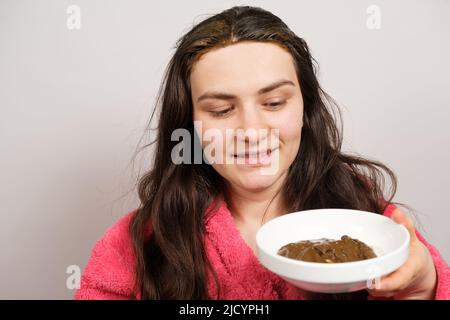 Une femme brune applique un mélange naturel d'herbes ayurvédiques à ses cheveux, masque de cuir chevelu et de gommage, soins des cheveux à la maison. Banque D'Images