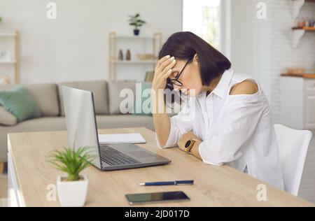 Femme stressée, fatiguée et frustrée qui a un épuisement assis à son bureau de travail Banque D'Images