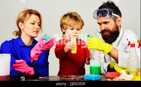 La famille nettoie ensemble. Mère et père enseignent à petit fils nettoyer avec un spray nettoyant et une éponge. Banque D'Images