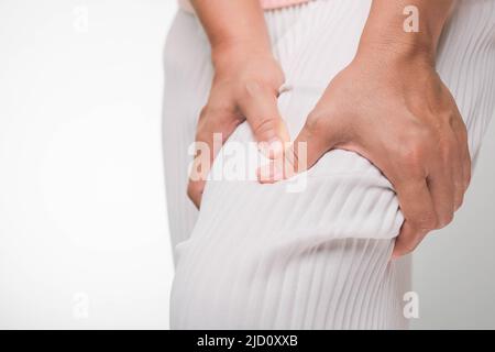 Femme tenant les mains sur son genou souffrant de douleurs au genou, de douleurs articulaires, d'arthrite et de problèmes de tendon sur fond blanc. Gros plan. Problèmes de santé, co Banque D'Images