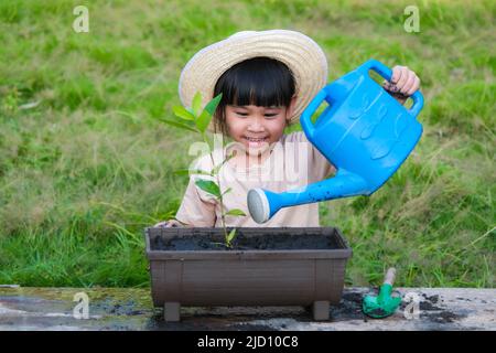 Une petite fille portant un chapeau aide sa mère dans le jardin, un petit jardinier. Jolie fille plantant des fleurs dans des pots à vendre. Petite entreprise familiale Banque D'Images