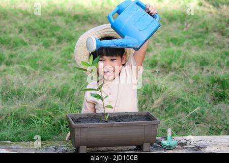 Une petite fille portant un chapeau aide sa mère dans le jardin, un petit jardinier. Jolie fille plantant des fleurs dans des pots à vendre. Petite entreprise familiale Banque D'Images