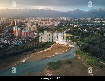 Tir de drone aérien de la rivière Big Almaty et du lac Sayran avec gratte-ciel et montagnes enneigées dans la ville d'Almaty, au Kazakhstan Banque D'Images