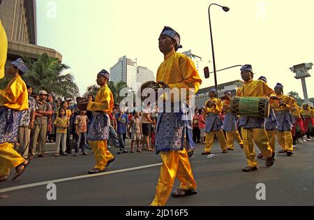 Des hommes portant une tenue traditionnelle de Riau jouant des instruments percussifs lorsqu'ils participent à une parade lors du Carnaval de Jakarta en 2004 dans le centre de Jakarta, Jakarta, Indonésie. Banque D'Images