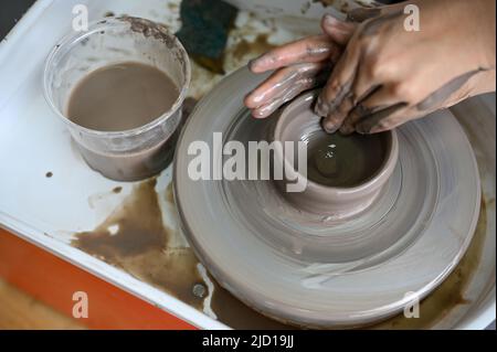 Une femme fait une tasse en céramique sur la roue de potter dans l'atelier d'artisanat en argile. Vue de dessus, image rognée Banque D'Images