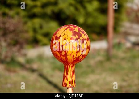 Boule de verre rouge et orange décoration de jardin. Boule de verre en verre métallurgique comme décoration pour lit de fleur ou clôture. Banque D'Images