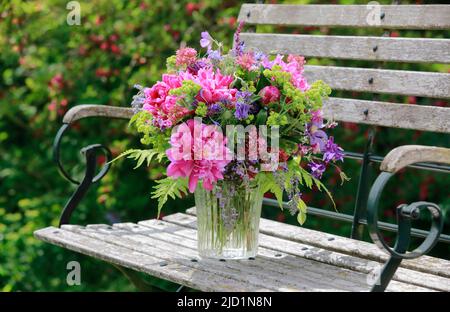 Bouquet coloré dans les tons rouge, rose et violet avec des pivoines et des columbines, supports en vase de verre sur le jardin décoratif en bois bouquet coloré Banque D'Images