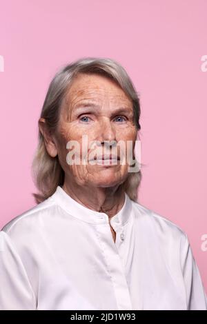Portrait d'une femme âgée sur fond rose Banque D'Images