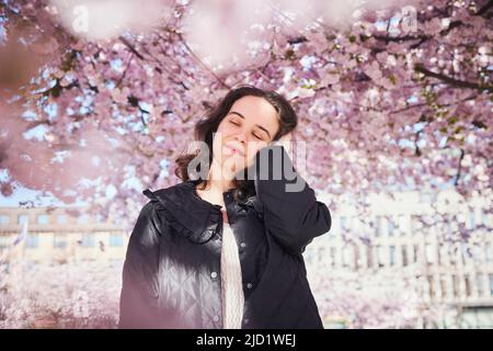 Jeune femme debout sous la fleur de cerisier Banque D'Images