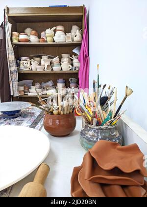 Tasses, tasses et pots en céramique sur une table dans un atelier de poterie. Banque D'Images