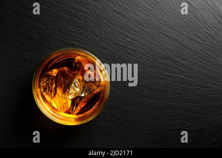 vue de dessus d'un verre de whisky sur une surface en pierre noire avec espace de copie Banque D'Images