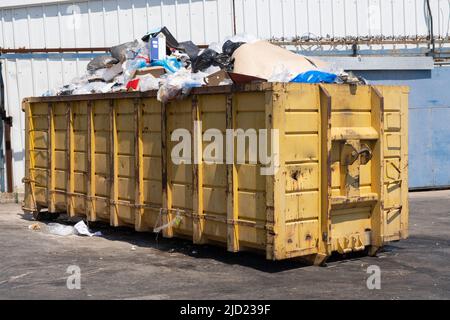 Immense grande poubelle surchargée remplie de déchets près du marché. Banque D'Images
