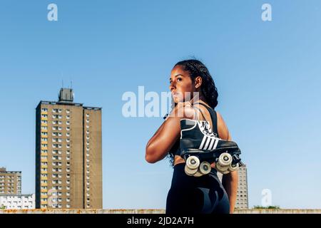 Vue arrière d'une jeune femme noire portant ses patins à roulettes, arrière-plan urbain. Banque D'Images