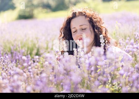 Portrait romantique de fille appréciant le parfum de lavande rose avec les yeux fermés dans un champ le jour ensoleillé. La fille marche un champ violet de fleurs. Le détox numérique est lent. Mise au point sélective douce Banque D'Images