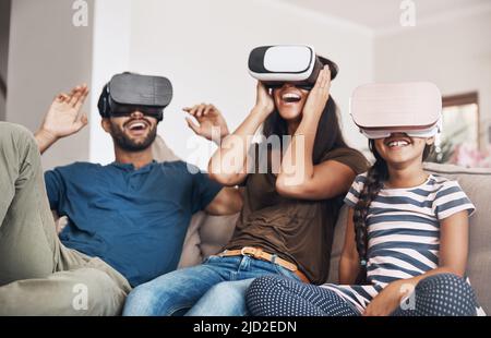 L'avenir du divertissement familial est là. Photo d'une jeune famille utilisant des micro-casques de réalité virtuelle ensemble à la maison. Banque D'Images