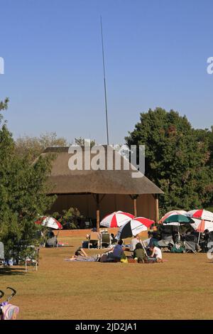 Hutte et visteurs sous parasols sur chaises, Pretoria National Botanical Garden, Pretoria/Tshwane, Gauteng, Afrique du Sud. Banque D'Images