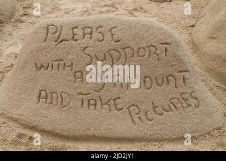 Sculpture de sable 'Veuillez soutenir avec toute la quantité et prendre des photos', plage d'Umfolozi, KwaZulu Natal, Afrique du Sud. Banque D'Images