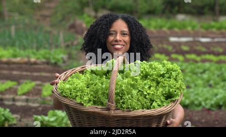 Une femme noire montrant des légumes biologiques à la petite ferme de jardin communautaire. Personne cultivant des lettres Banque D'Images