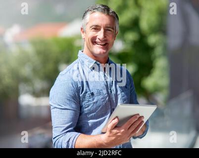 La technologie sans fil rationalise mes tâches quotidiennes. Portrait d'un homme d'affaires habillé de manière décontractée utilisant une tablette numérique à l'extérieur. Banque D'Images