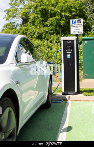 Woodbridge Suffolk Royaume-Uni Mai 18 2022: Une voiture électrique Tesla modèle 3 charge à la station de charge de branchement dans un parking public à Suffolk, Royaume-Uni Banque D'Images