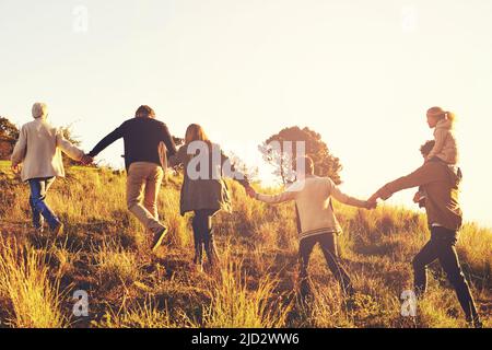 Et les aventures de sothe commencent. Une famille de plusieurs générations marchant sur une colline herbeuse au soleil. Banque D'Images