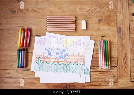 La créativité, c'est l'intelligence qui s'amuse. Photo d'un dessin avec des fournitures de peinture et des crayons sur une table en bois. Banque D'Images