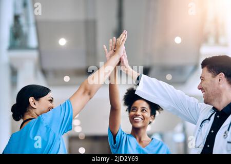 Nous l'avons fait ensemble. Photo d'une équipe diversifiée de médecins se donnant un haut cinq dans un hôpital. Banque D'Images