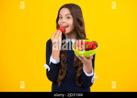 Joyeux sourire enfant de l'adolescence tenir le bol de fraise sur fond jaune. Nourriture saine et naturelle en vitamines pour les enfants, saison des fraises. Banque D'Images