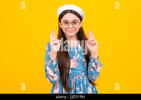 Adolescent heureux, émotions positives et souriantes. Bonne adolescente croise les doigts, anticipe entendre de bonnes nouvelles, isolé fond jaune. Heureux Banque D'Images