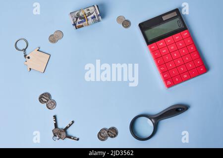 Concept d'achat et de vente de maisons, prix immobiliers, prêt, économiser de l'argent pour l'investissement de biens d'affaires. Calculatrice vue de dessus, petit modèle de maison, argent, pièce, sur fond bleu avec espace de copie. Banque D'Images