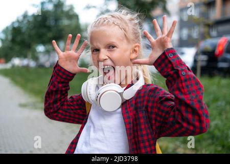 retour à l'école. Happy Girl excitée avec des sacs à dos jaunes qui jouent dans la rue près de l'école après une pandémie. Les élèves sont prêts pour la nouvelle année Banque D'Images