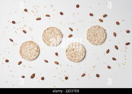 Pile de gâteaux de riz, de flocons d'avoine et de noix sur fond blanc. Des collations saines Banque D'Images