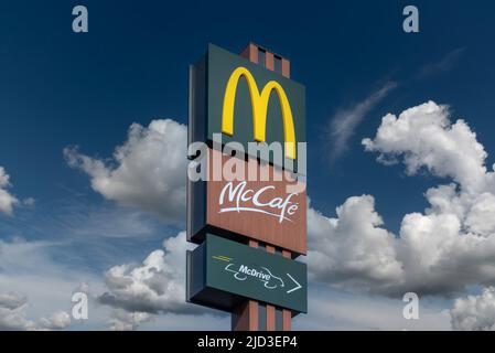 Savigliano, Italie - 16 juin 2022 : panneau McDonald's avec logo McCafe et McDrive sur ciel bleu avec nuages blancs. La McDonald's Corporation est le l du monde Banque D'Images